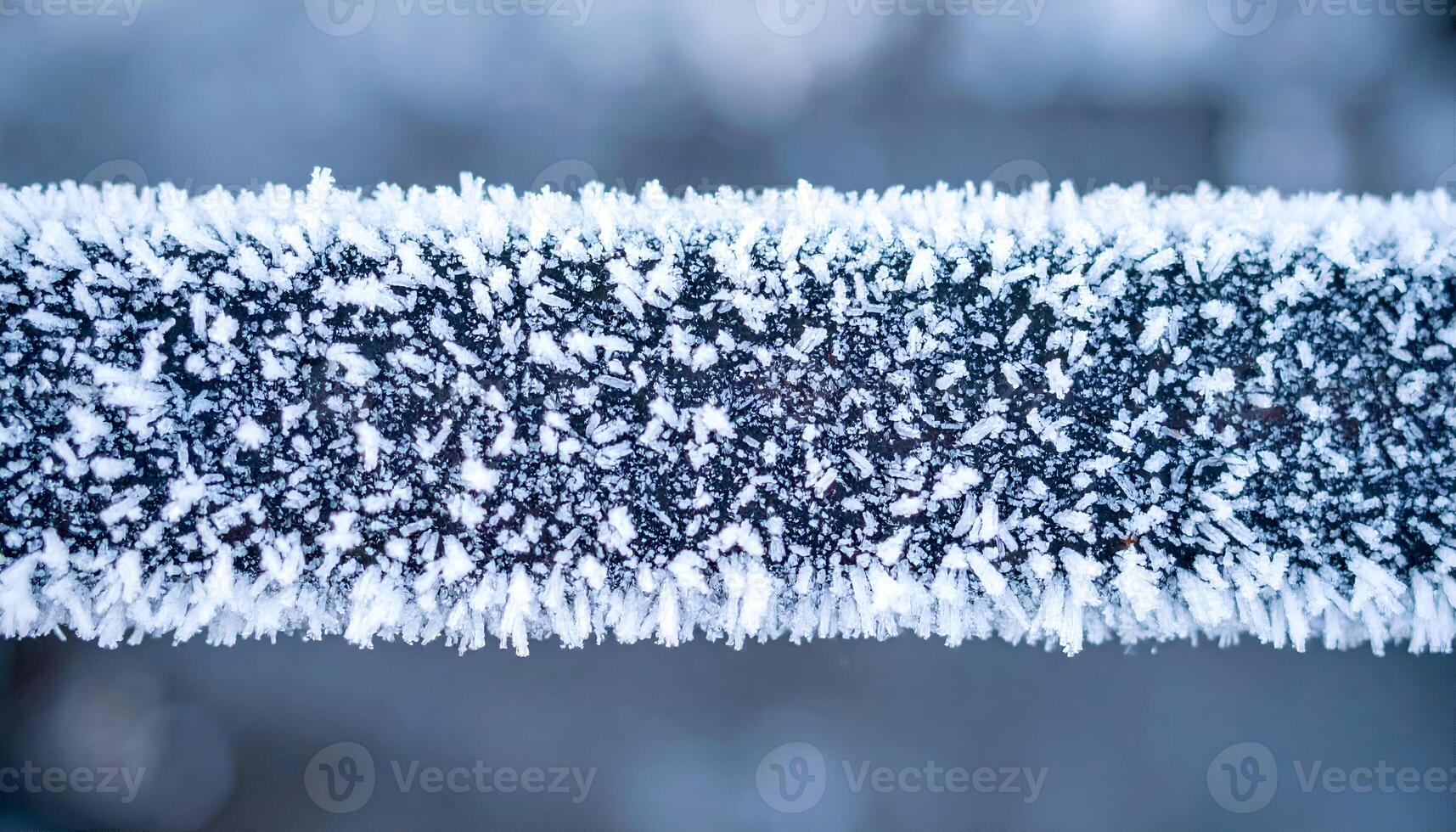 macro close-up of frost crystals on metal railing in winter, showing icy texture and sharp frozen patterns in cold weather conditions photo