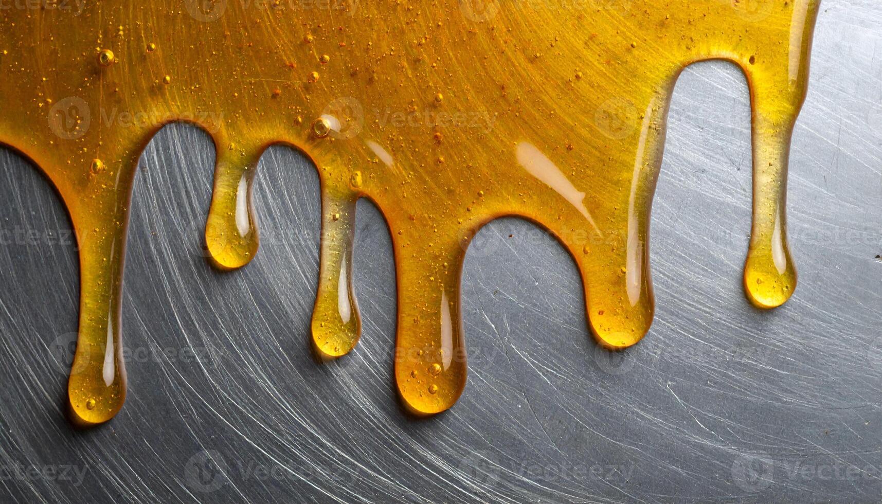 dripping honey on brushed metal surface, close-up top view of golden syrup flowing in glossy lines for sweet dessert background or food texture design photo