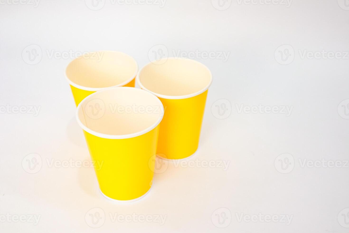 Three bright yellow paper cups isolated on white background, creating a clean and simple composition, vibrant and minimalist photo