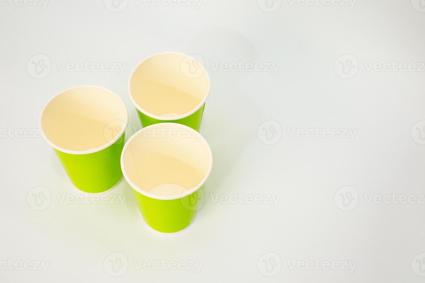 Three bright green paper cups arranged on a plain white background with copy space photo