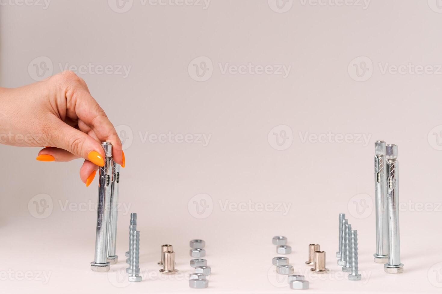 screws and nuts and bolts, stand on a light background, the hand moves the bolt construction concept photo