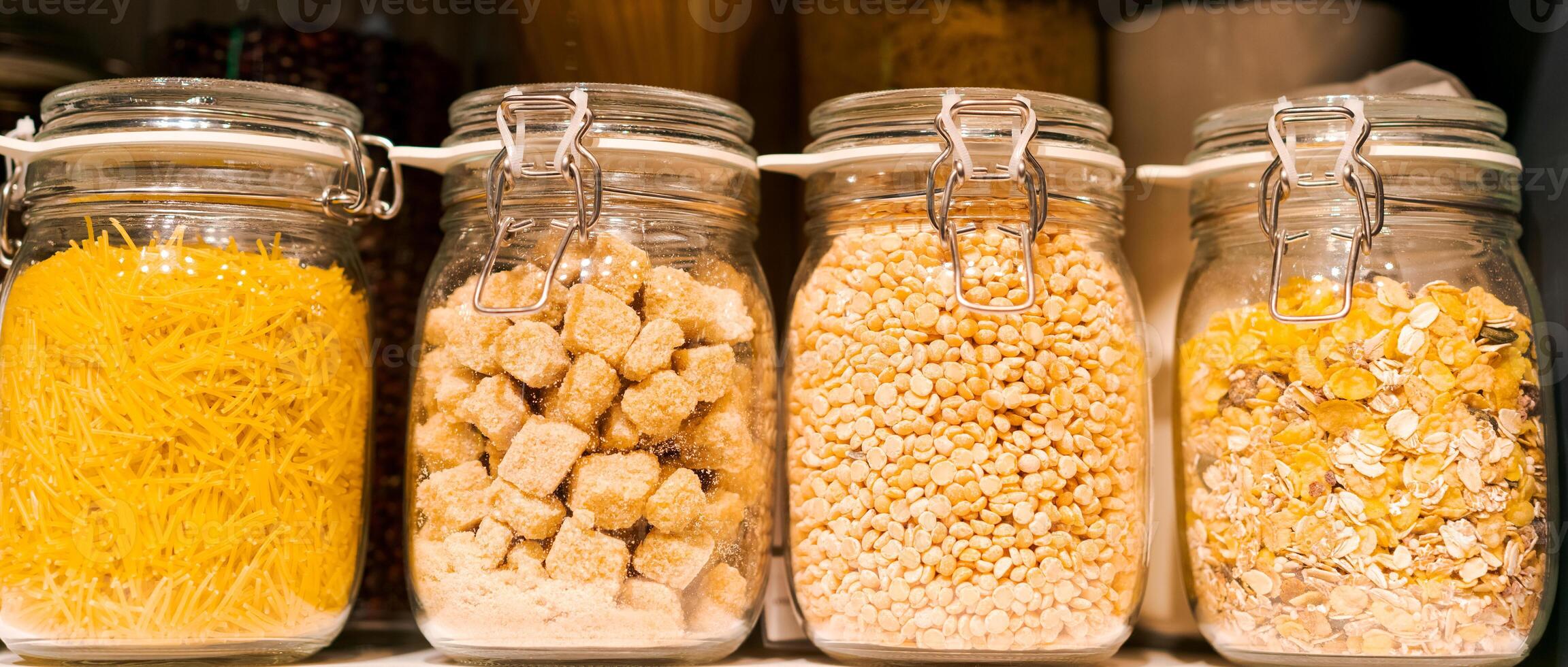 banner stand in a row of glass jars on a shelf with pasta, the concept of organizing a kitchen space photo