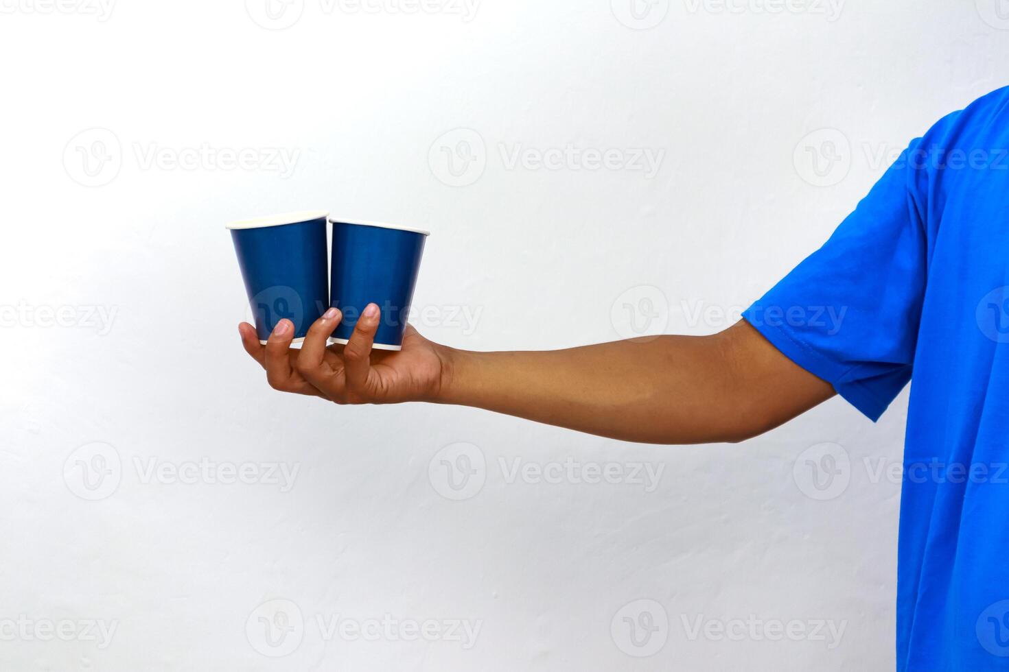 Person in Blue Shirt Holding Two Blue Paper Cups Against White Background photo
