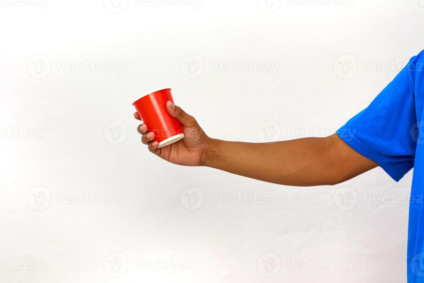 Hand holding a red plastic cup against a white background, isolated studio shot photo