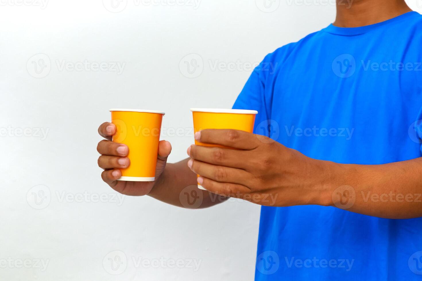 Man in blue shirt holding two yellow paper cups, isolated on white background, studio shot photo