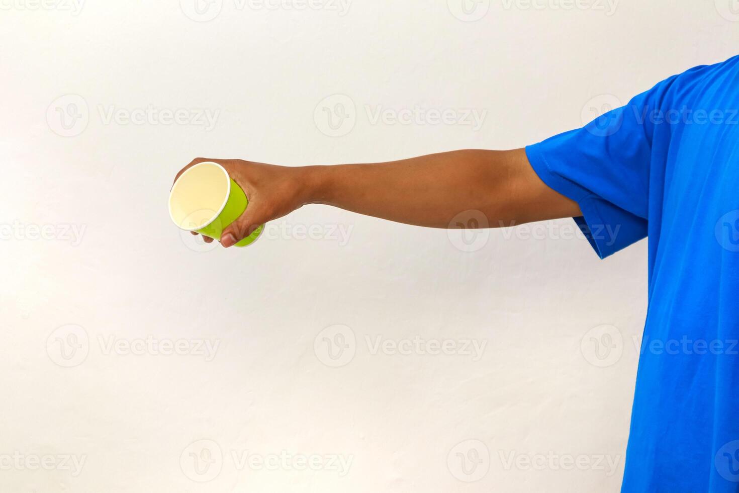 Person holding a green disposable cup with outstretched arm against a white background photo