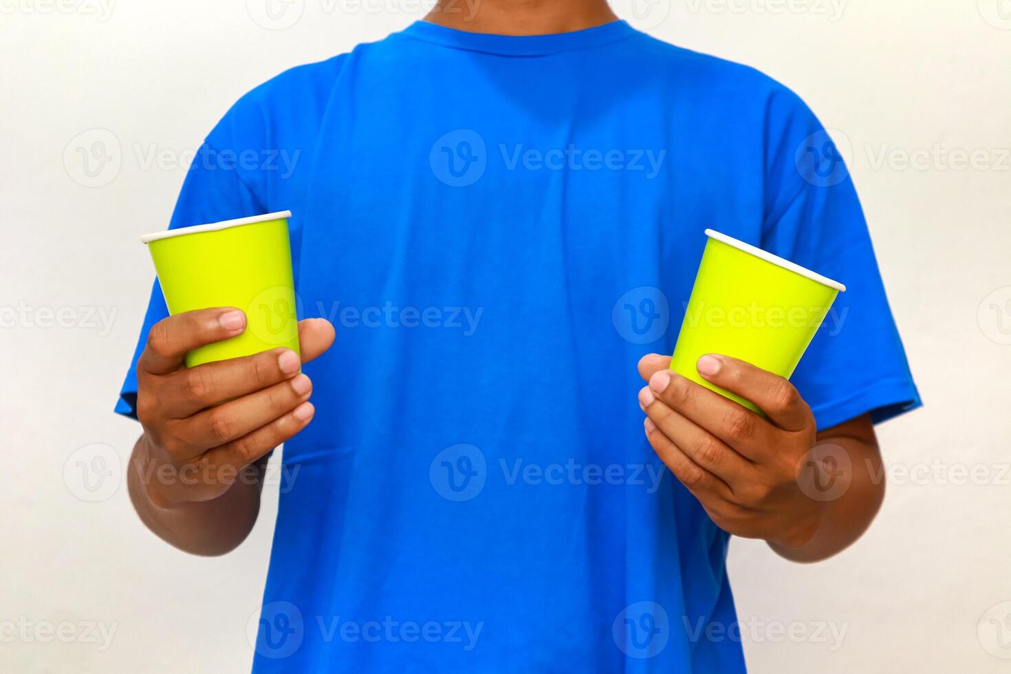 Person in blue shirt holding two light green disposable cups for serving drinks photo