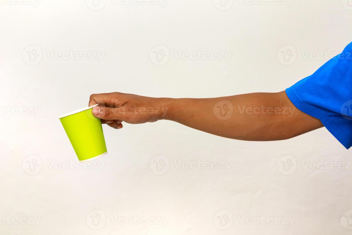 Hand offering a vibrant green paper cup, isolated on a clean white background, focusing on generosity photo