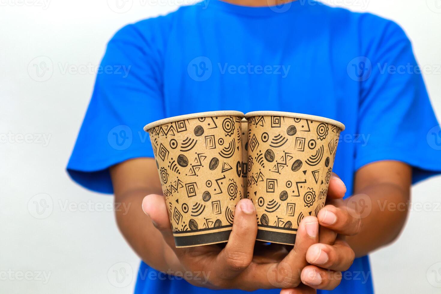 Person in Blue Shirt Holding Two Patterned Paper Coffee Cups in Hands photo