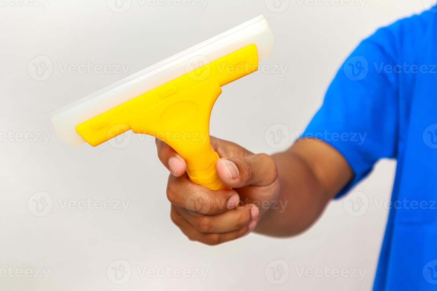 Hand Holding a Yellow Squeegee for Window Cleaning or Surface Wiping Tasks photo