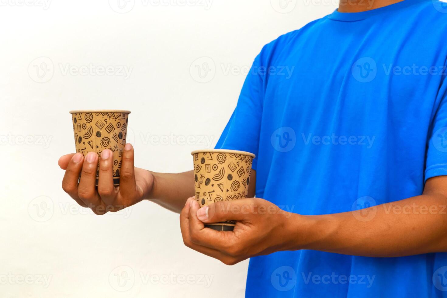 A man wearing a blue shirt holding two paper cups with abstract shapes design photo
