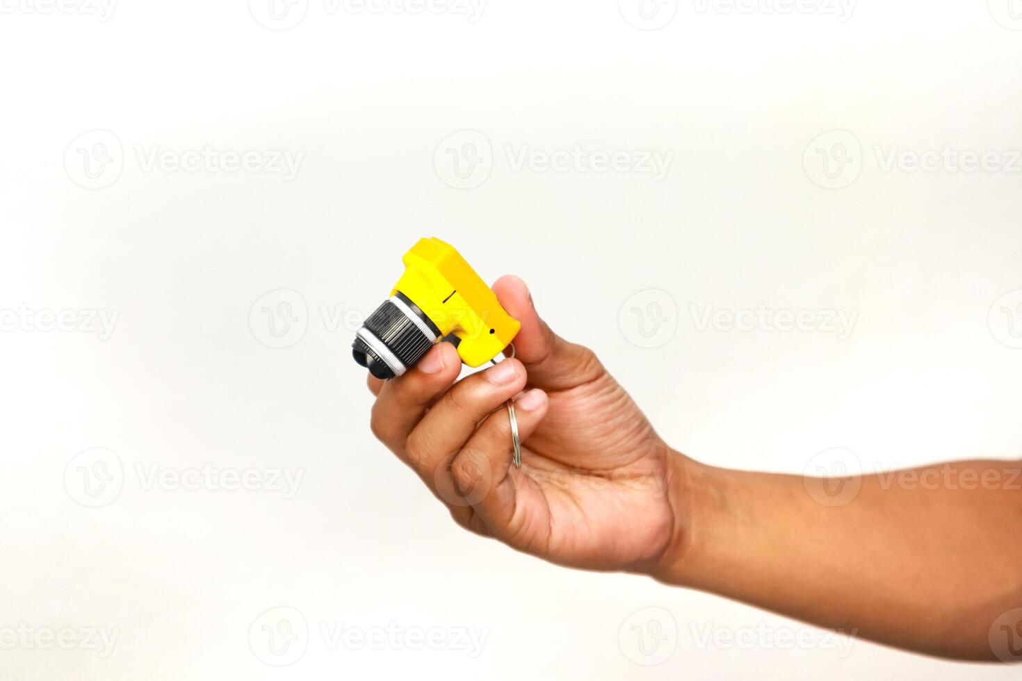 A person's hand holding a yellow macro lens attachment for a mobile phone camera with a white background, studio photography photo