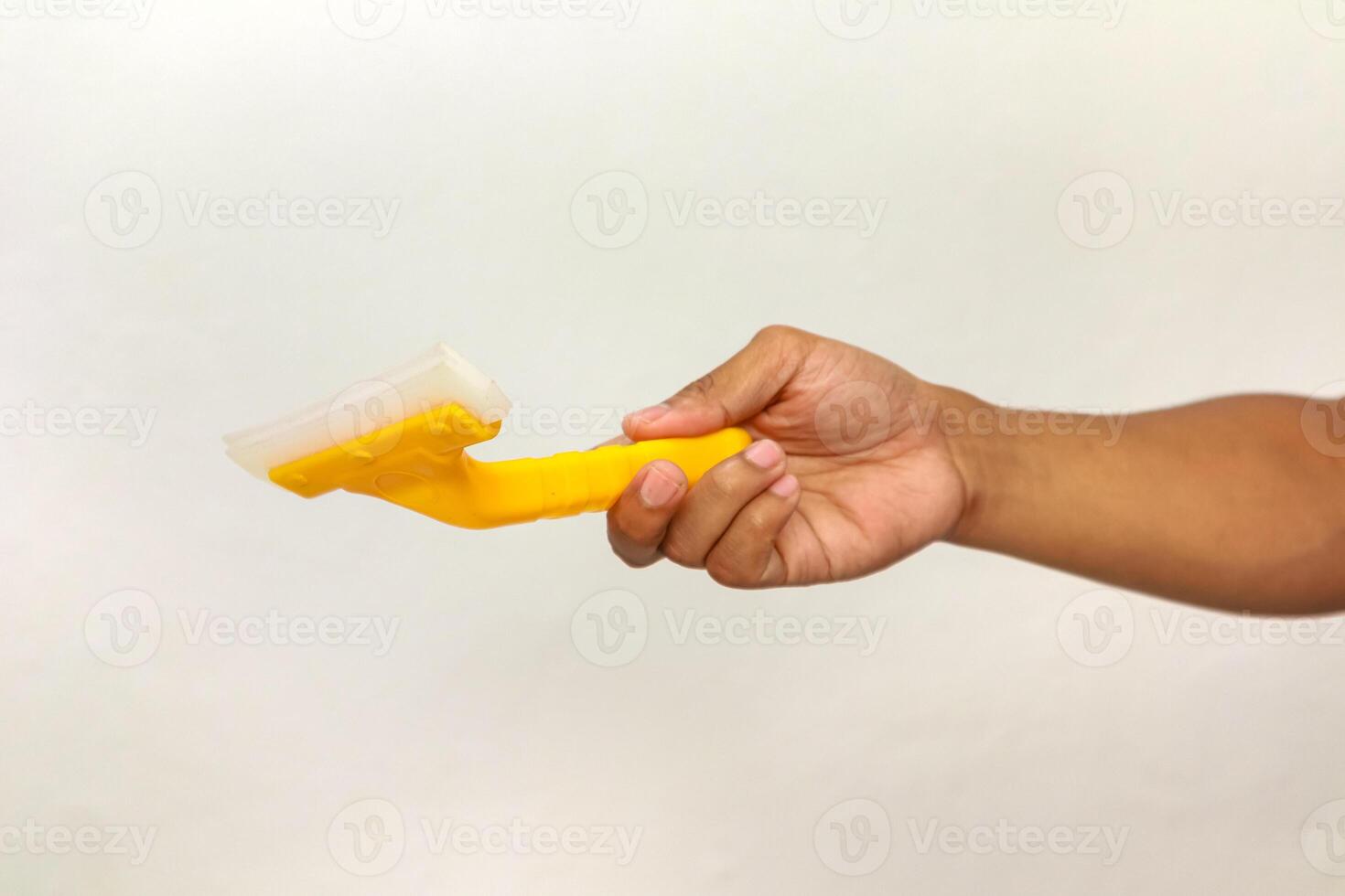 Hand holding a yellow and white squeegee against a white background, cleaning tool photo