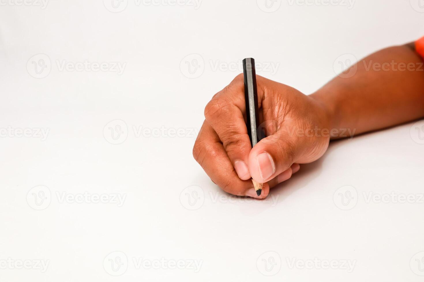 A hand writing with a short, black pencil on a white surface provides creative space photo