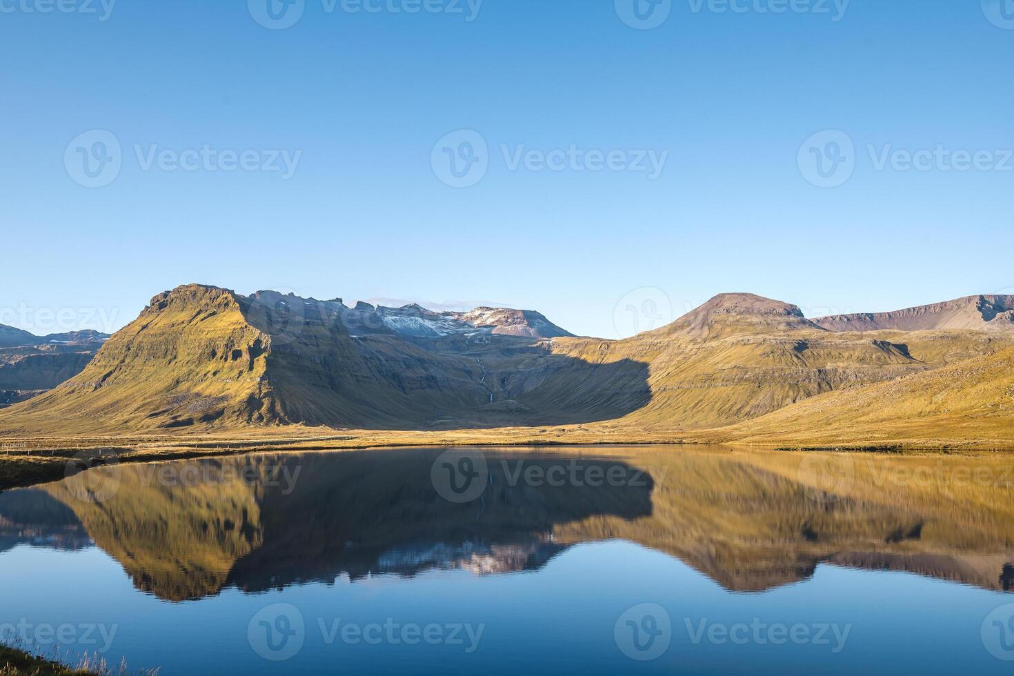 mountains reflect in a still lake on Snaefellsnes peninsula Iceland with glacier capped peaks and blue skies completing this serene and majestic natural scene photo