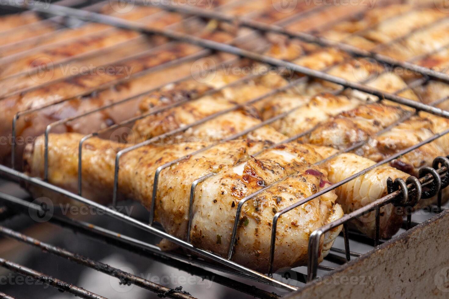 Close up chicken legs and sausages grilling on barbecue grill photo