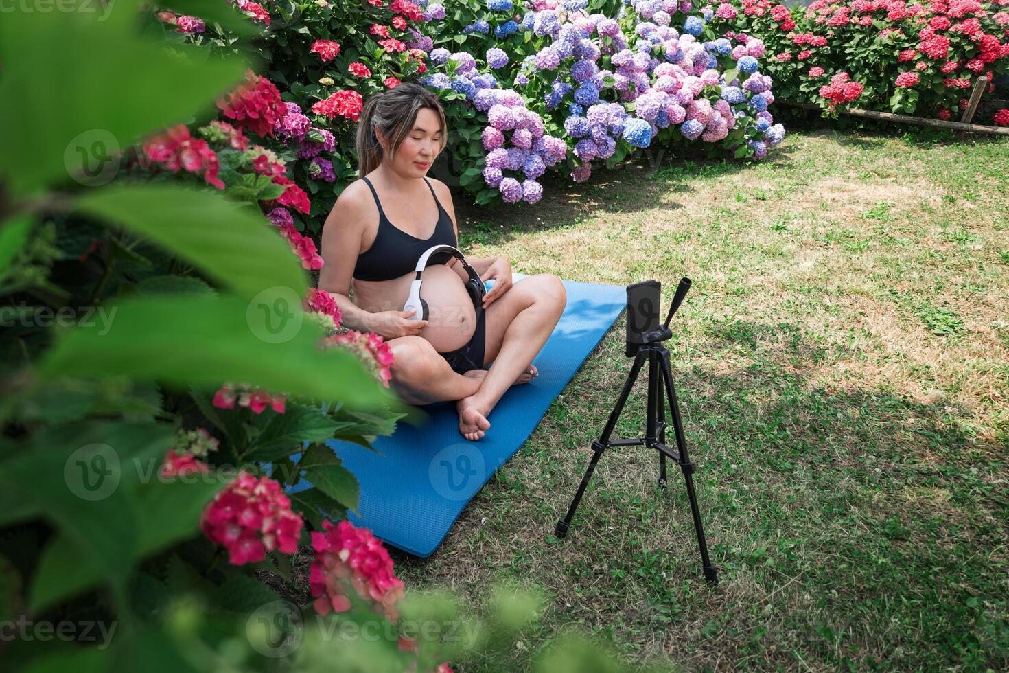 Pregnant influencer creating content for social media in garden photo