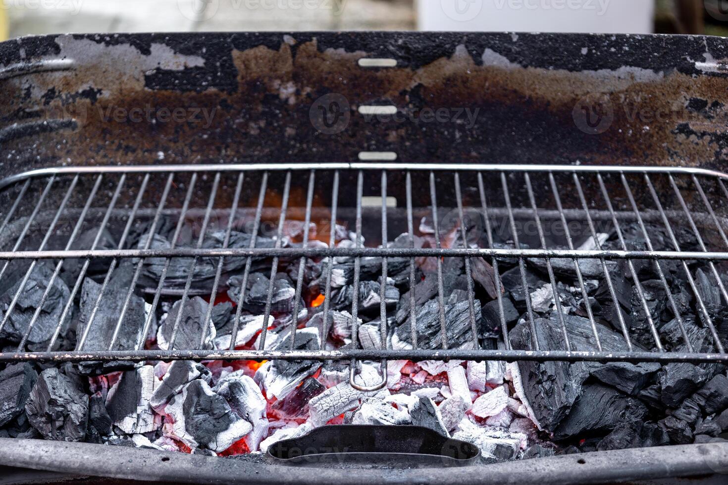 Glowing charcoal briquettes heating up empty grill grate outdoors photo