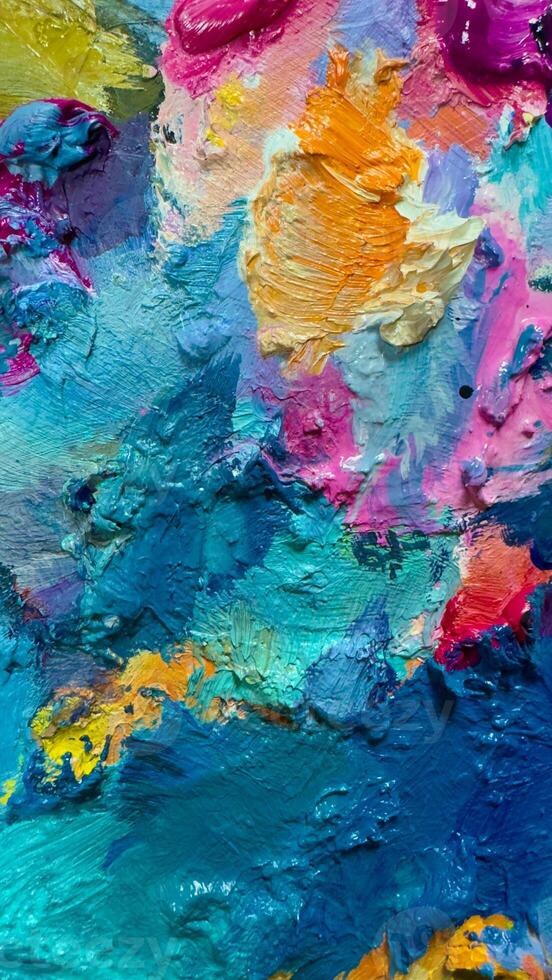 Background of bright oil-paint palette close-up pattern, blue, yellow, pink color texture photo