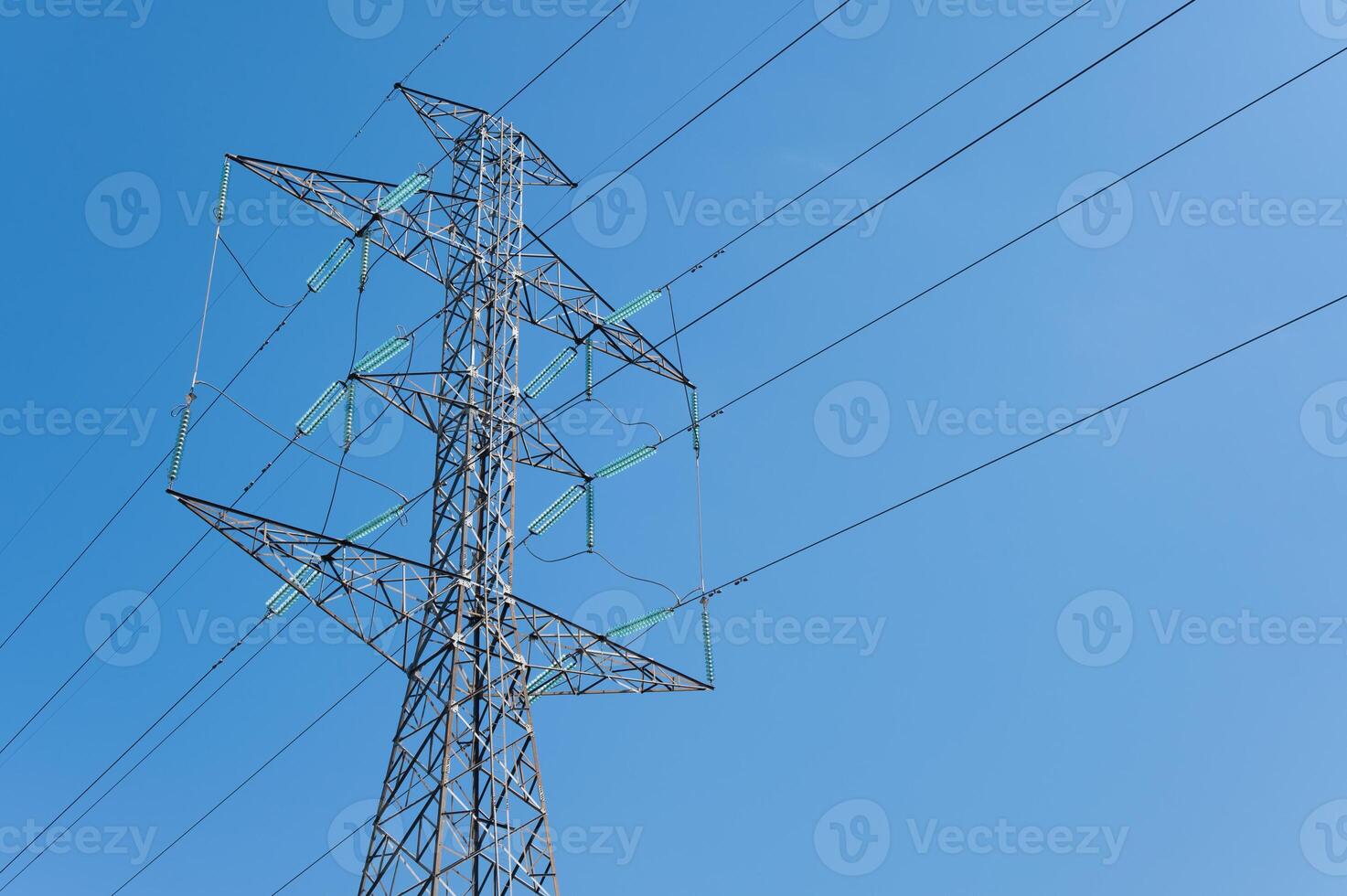 A transmission tower against blue sky. Transmission towers or electrical pylons carry large amounts of high-voltage current over long distances. photo