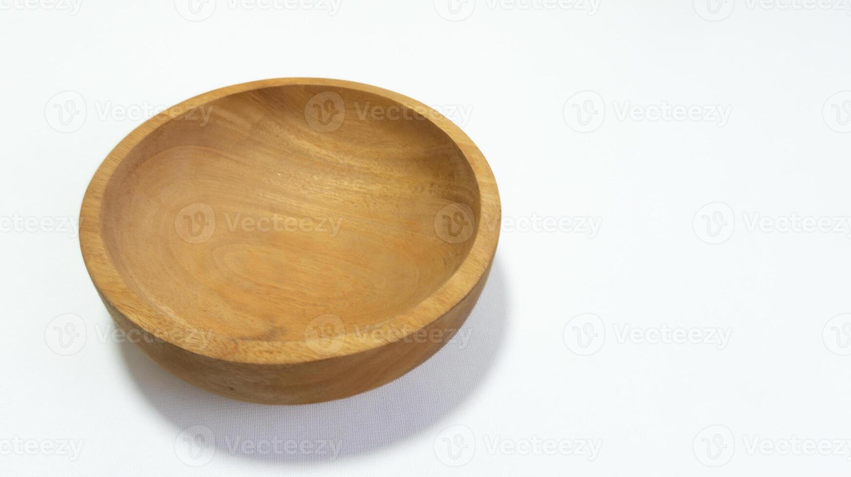 Close-up studio shot of an empty wooden bowl on a white surface displaying natural wood grain and simple craftsmanship with minimalist design photo