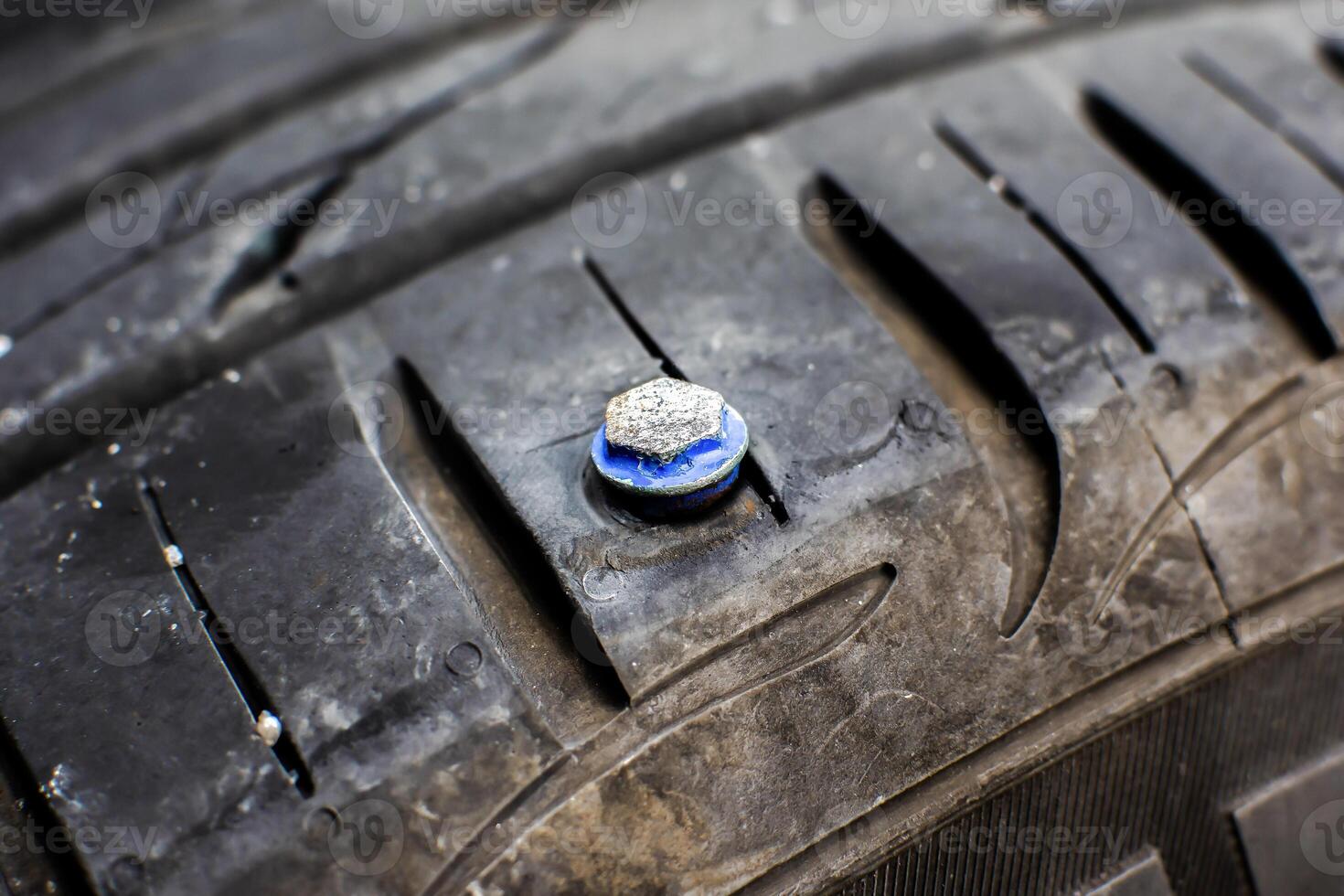 Flat Tire, A close-up of a car tire with a screw or nail embedded in the tread, indicating a puncture and the need for tire repair. photo