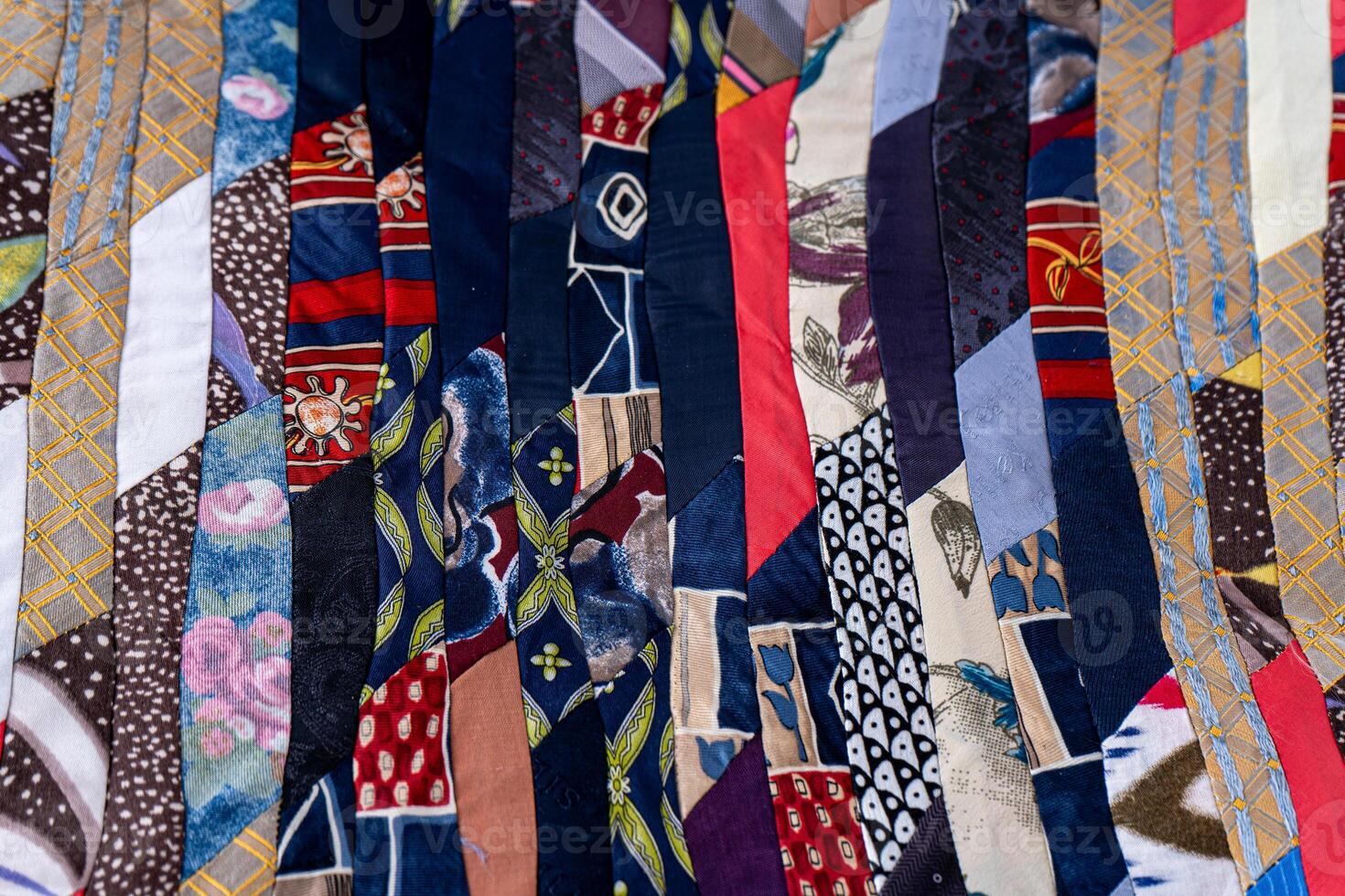 Patchwork Quilt Made of Repurposed Neckties. A fragment of multi-colored pieces of fabric sewn together. photo