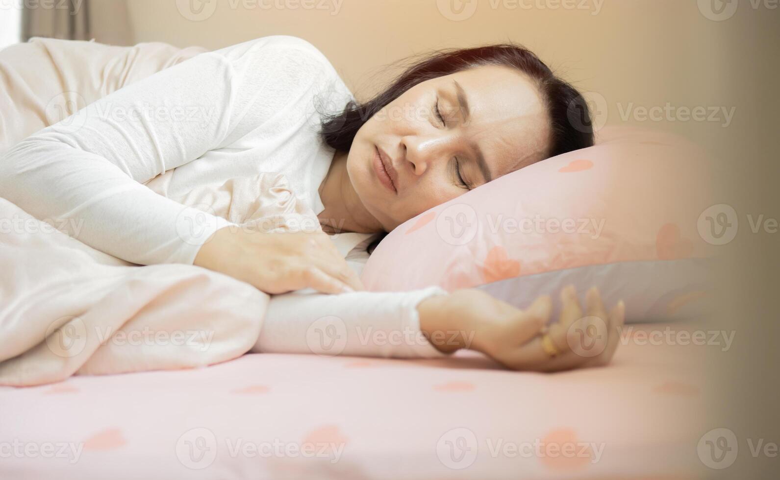 Woman sleeping. High angle view of beautiful young woman lying in bed and keeping eyes closed photo