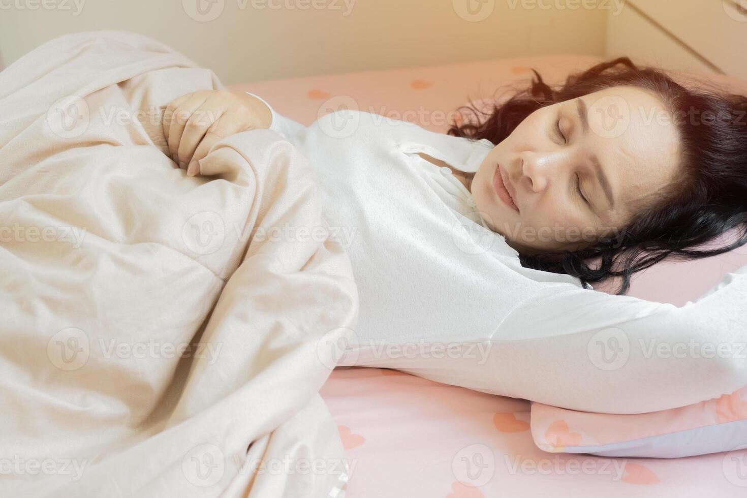 Shot of Asian woman lying asleep relaxing sleeping in cozy bed on soft pillow resting covered with blanket photo