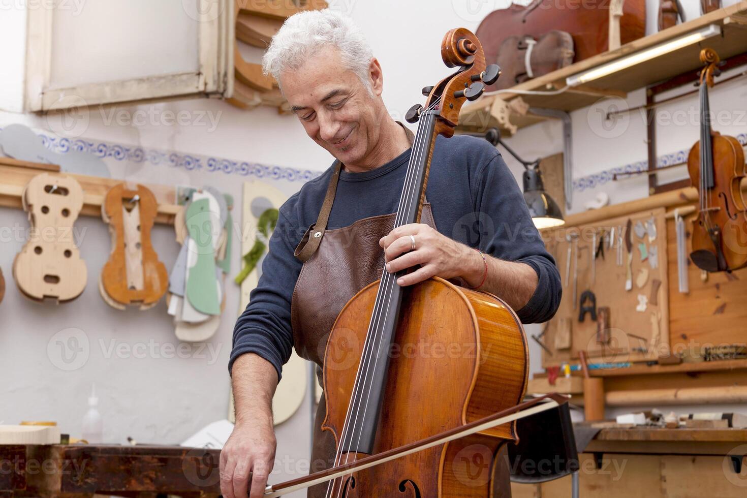 mature luthier playing a viola using the bow to test the sound quality at work photo