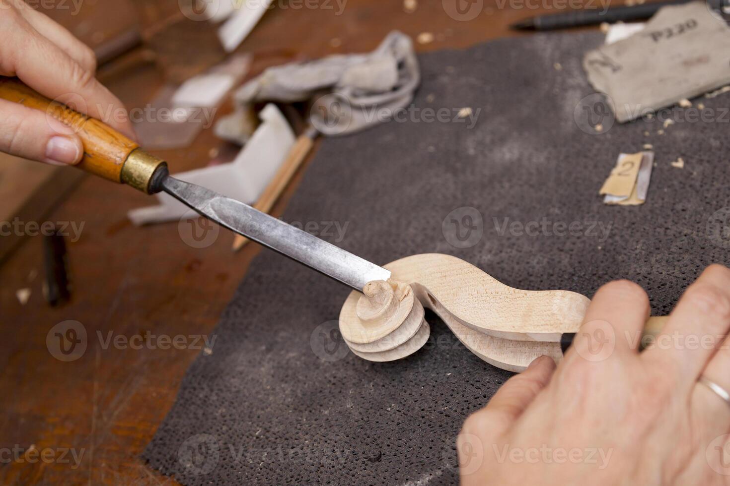 close-up on the hands of a craftsman luthier carving a violin neck in his workshop photo
