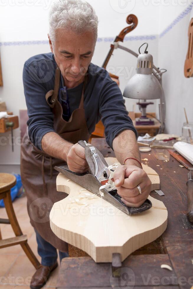 expert violin maker in the workshop creating a new violin from a piece of wood photo