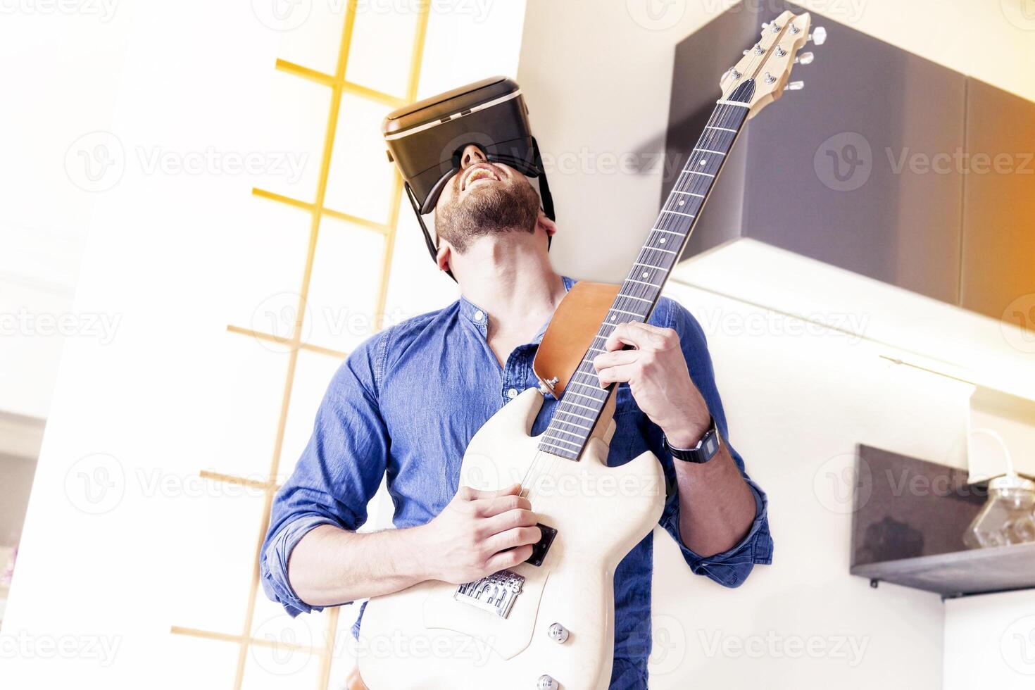 professional musician wearing a virtual reality headset giving a show at home playing electric guitar photo
