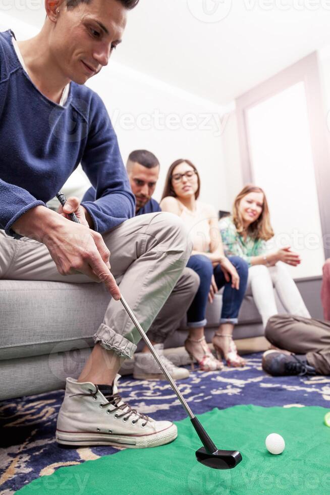 group of young adults have fun playing golf in the living room photo
