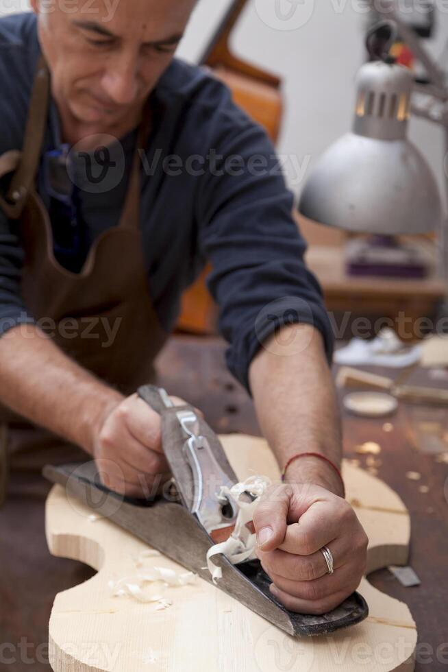 expert violin maker craftsman starting work on creating a new violin from a piece of wood photo