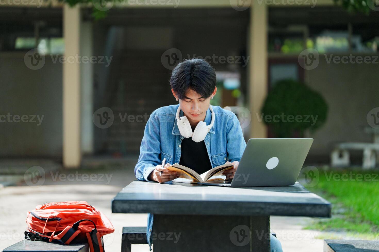 College student studying and reading on campus outdoor with laptop. photo