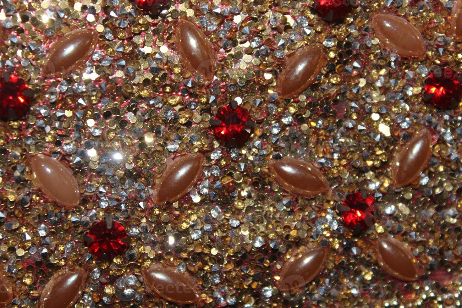 A close-up view of a textured surface adorned with an array of small, sparkling rhinestones in shades of gold and silver. photo