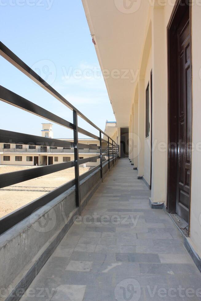 A two-story school building with a flat roof and cream-colored walls that forms a U shape with an open courtyard in the middle. photo