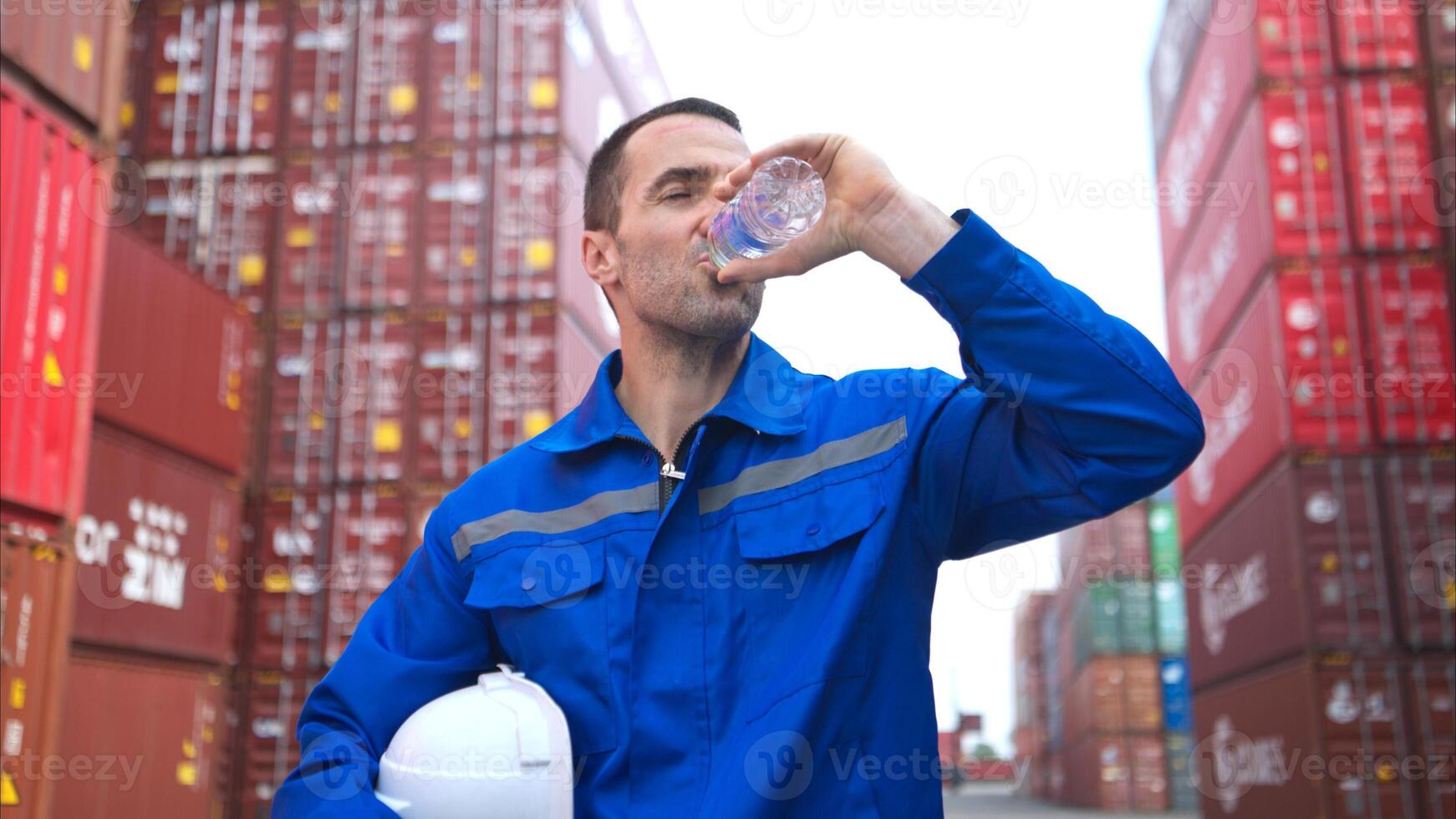 Container warehouse worker drinks water during break hours in the bright sunlight,61 photo