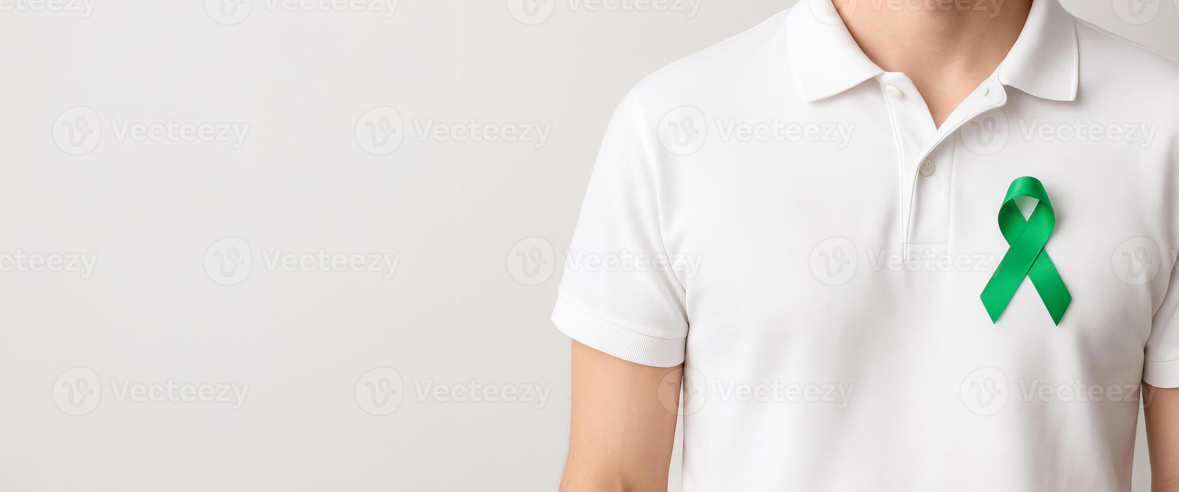 Man wearing white polo shirt with green ribbon. concept of health awareness, support for causes, mental health, organ donation, liver cancer, lymphoma, Wide banner, copy space, white background photo