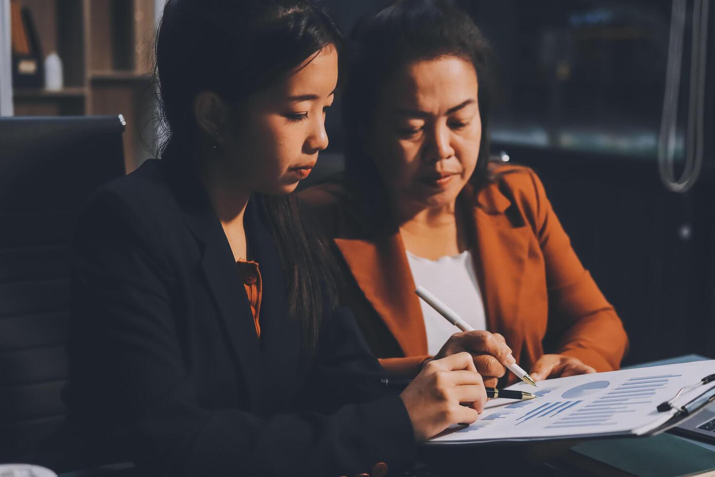 Two women in business attire working on a document photo