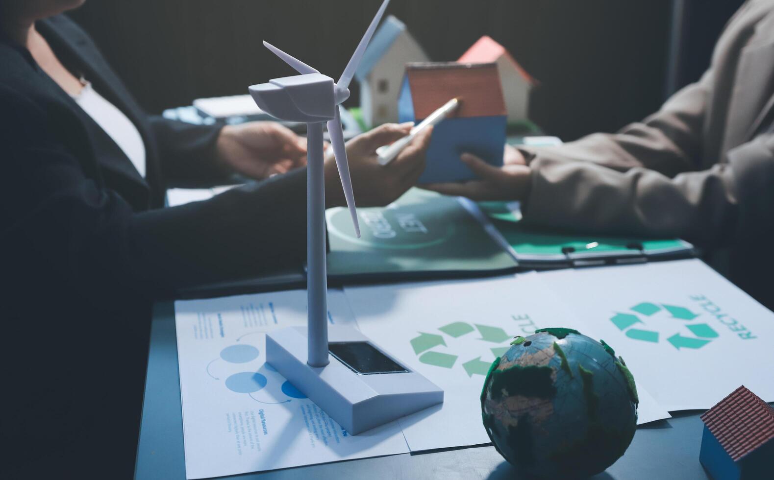 Two people are sitting at a table with a wind turbine photo
