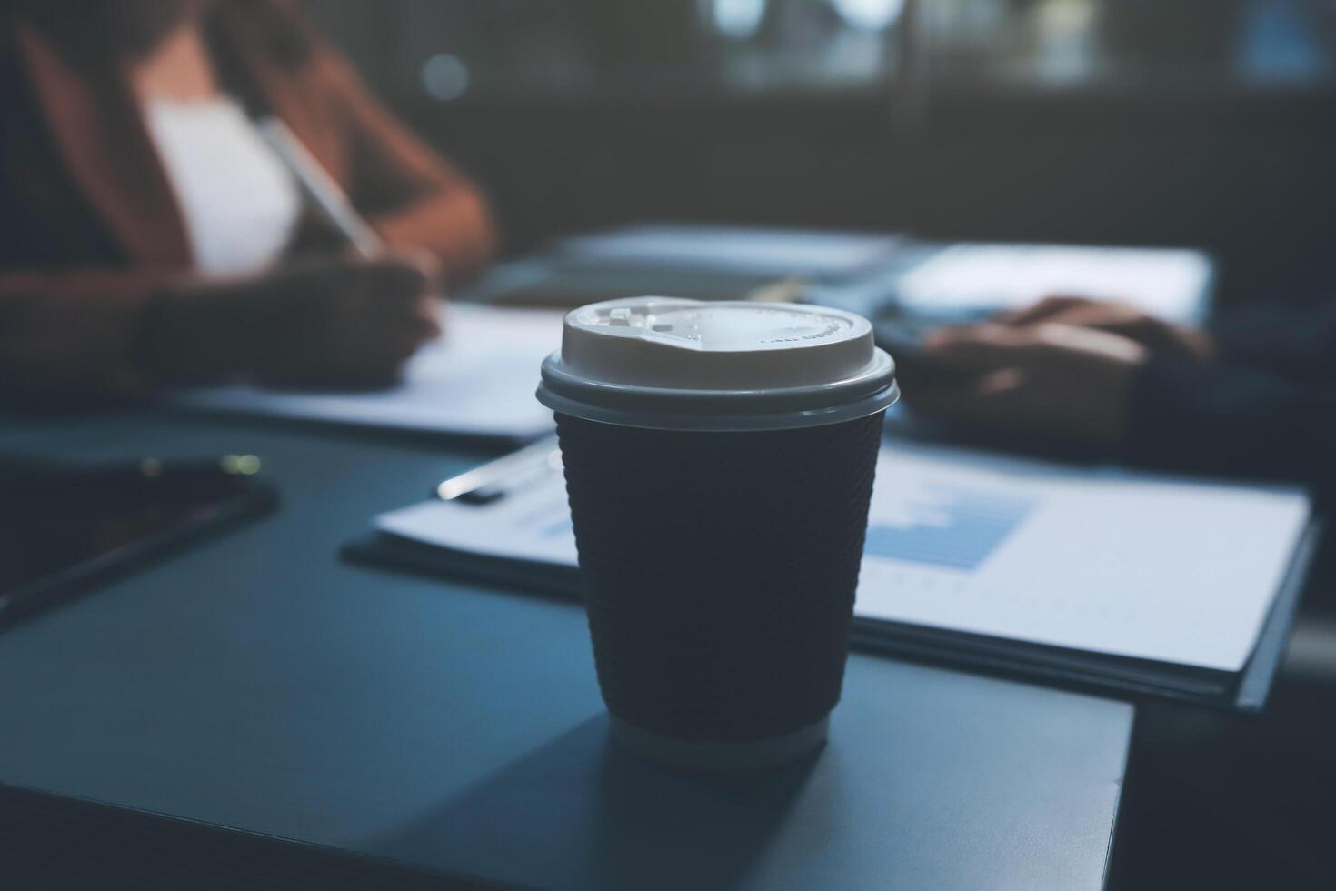 A coffee cup sits on a desk in front of a woman photo
