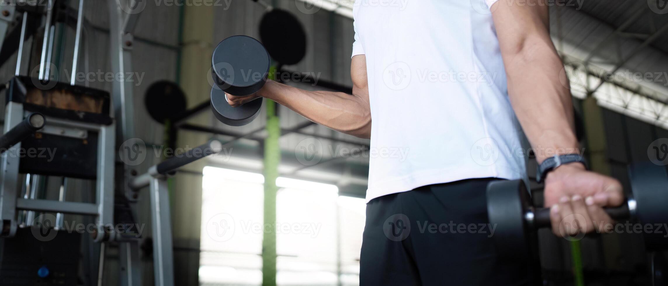 Focused Strength Training. Close-up of young man lifting dumbbells in gym. photo