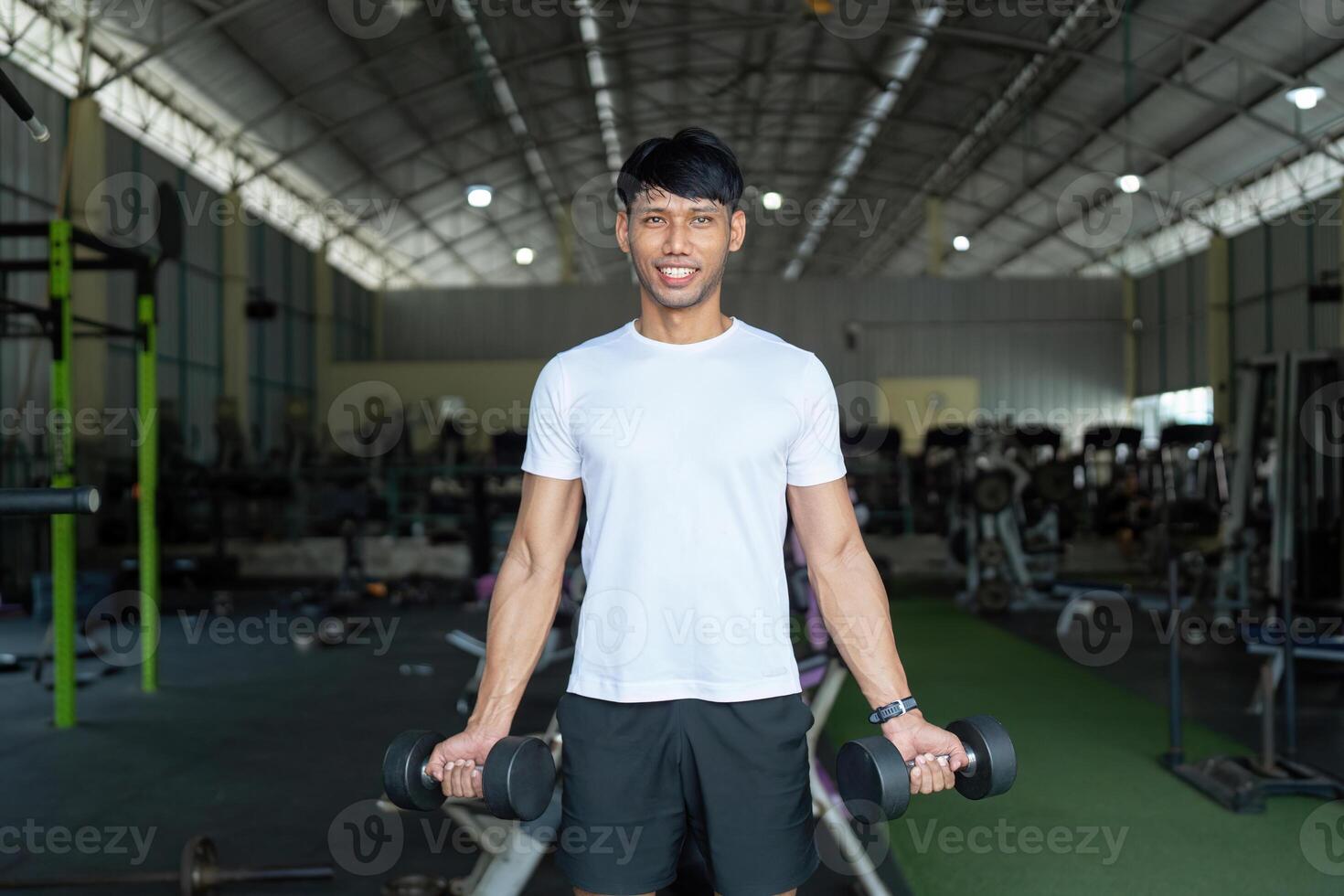 Fitness and Strength Training. Young man lifting dumbbells in gym for strength and wellness. photo