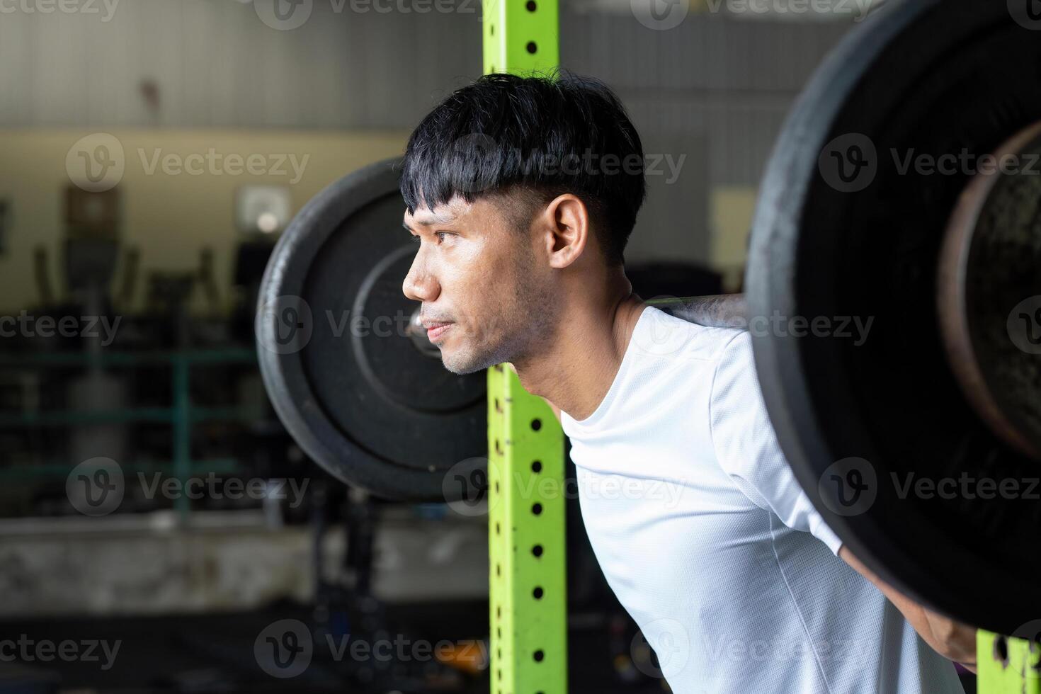 Strength Training. Man performing squat exercise with barbell in gym. photo