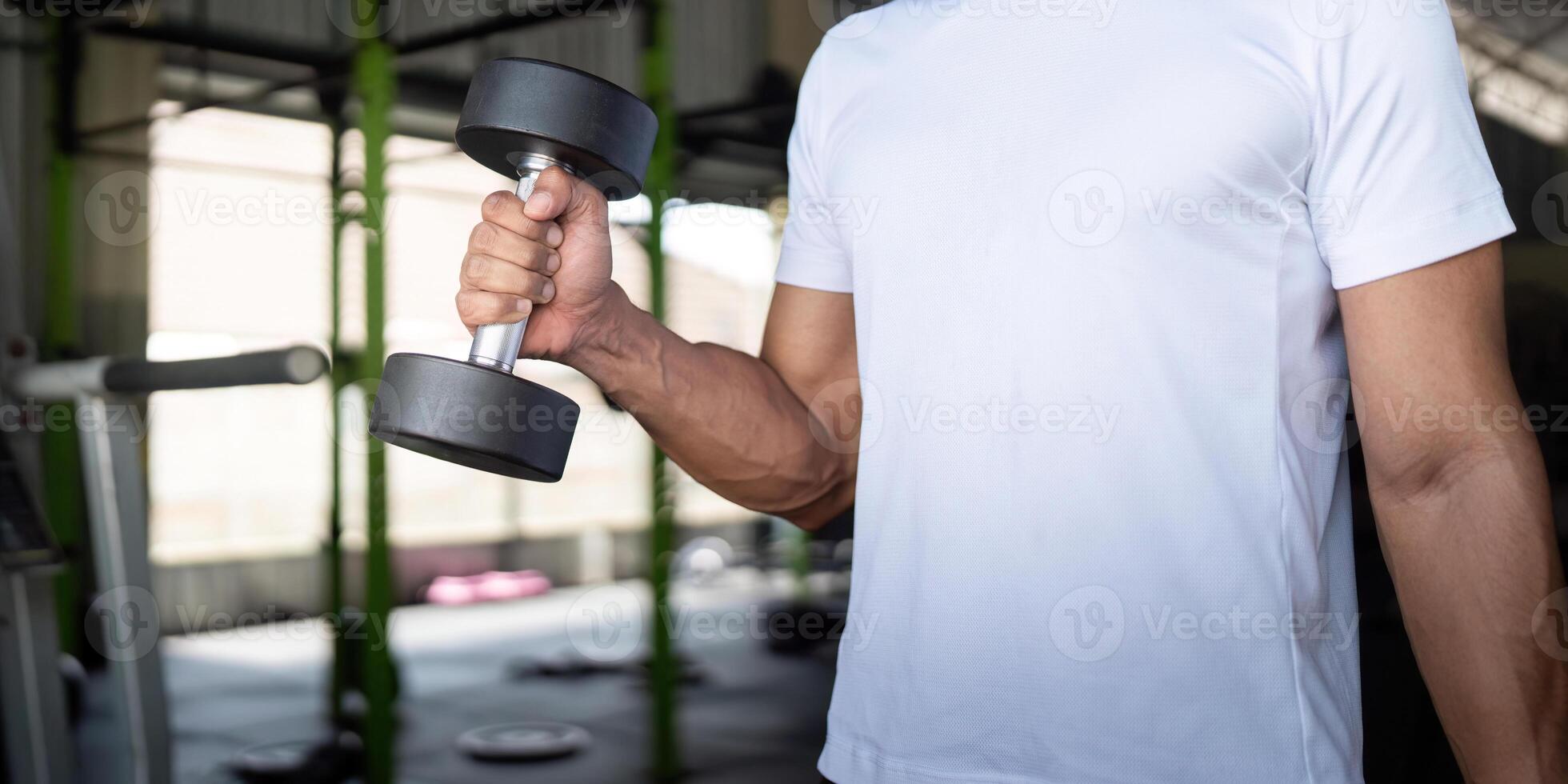 Focused Exercise. Young man lifting a dumbbell in gym for strength and fitness. photo