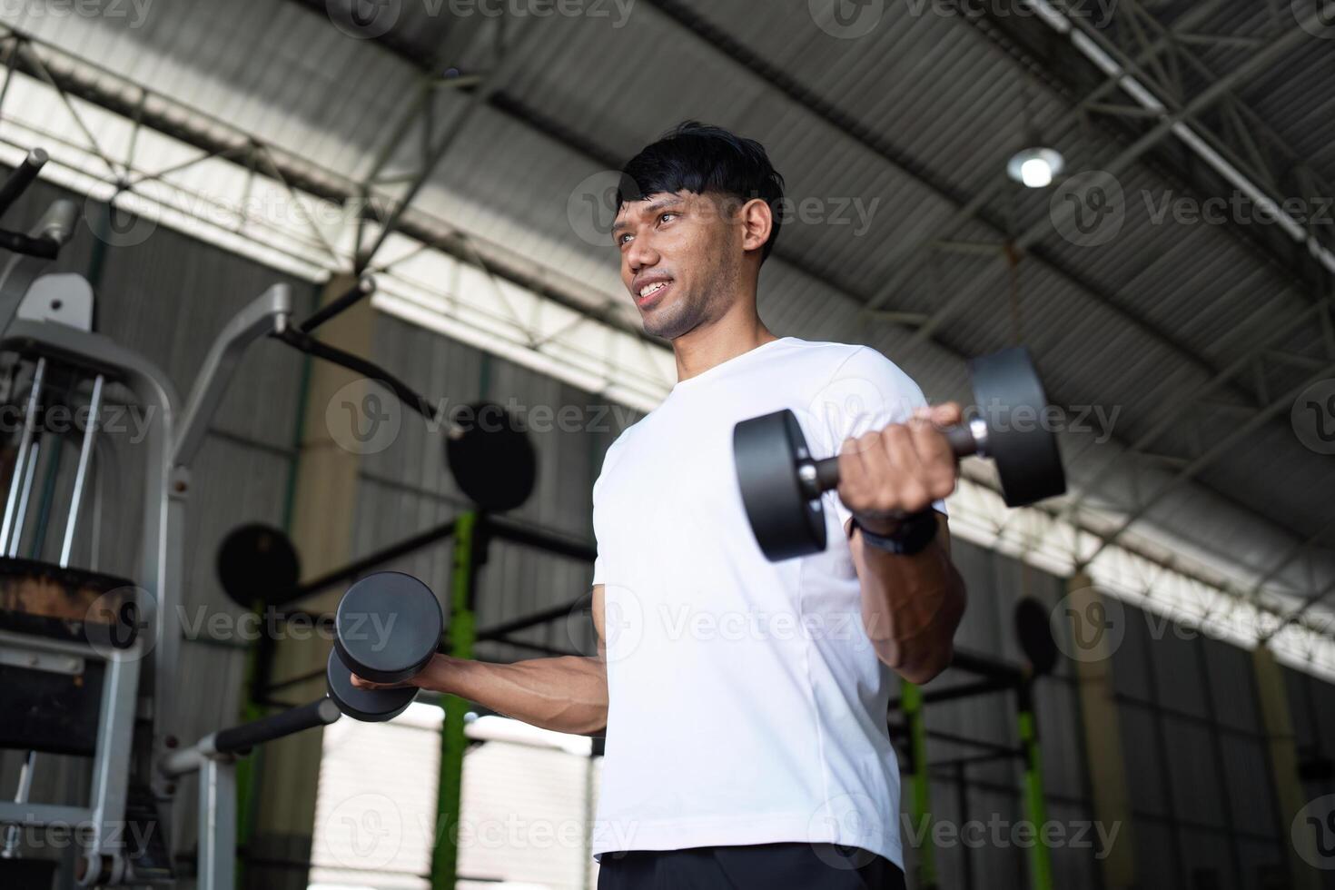 Strength Training Focus. Young man performing bicep curls with dumbbells in gym. photo