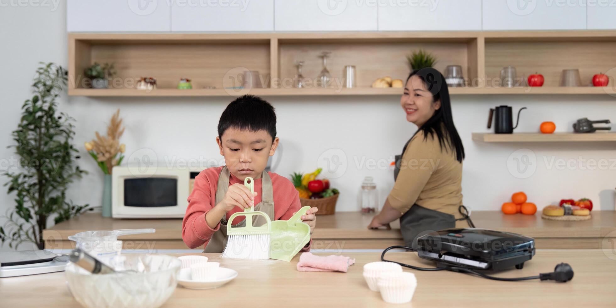 Cleaning and Family Time. A boy learning to clean while his mother prepares in the kitchen. photo