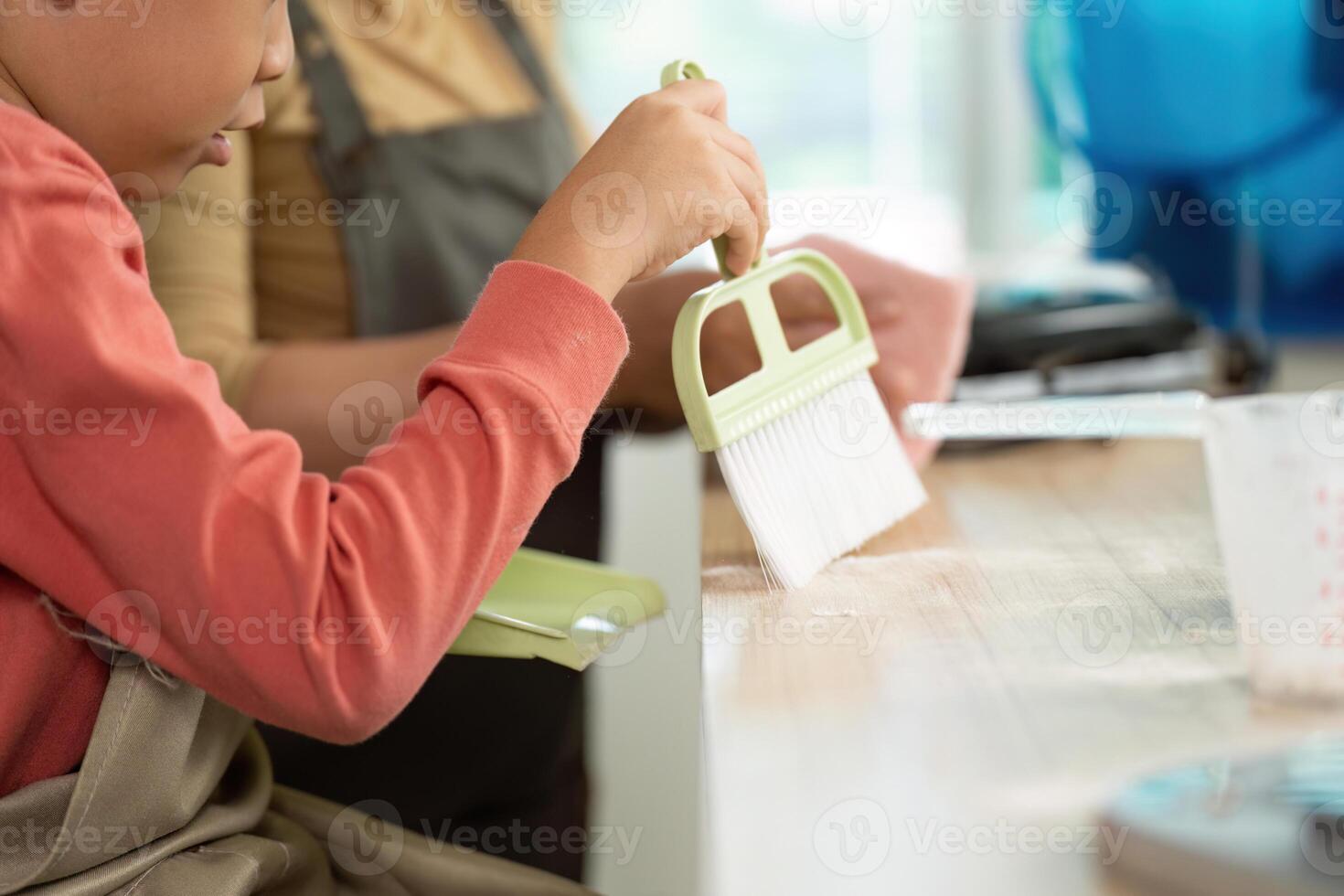 Cleaning and Organization. A child and adult engaged in kitchen cleaning activities. photo